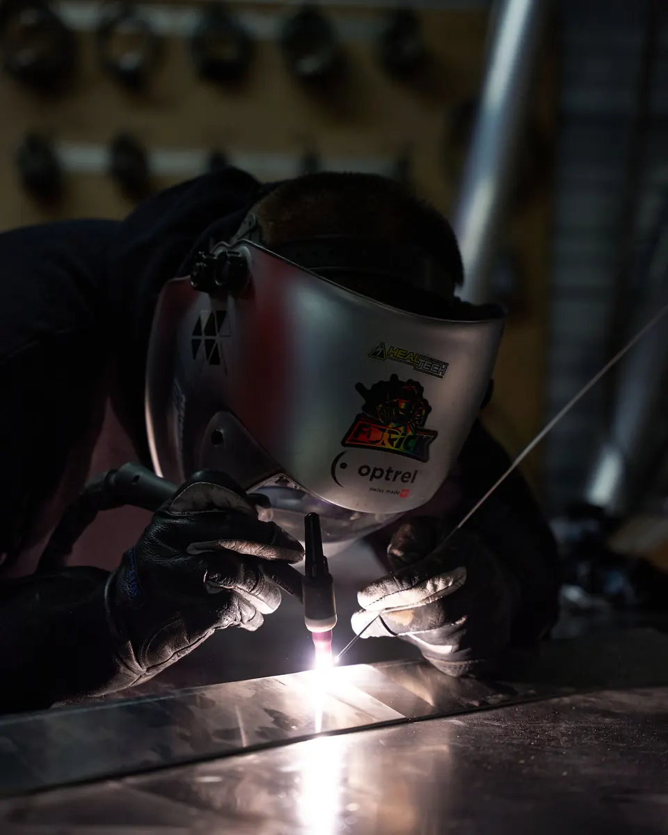 Soudeur en soudure TIG, casque baissé, arc lumineux sur la pièce